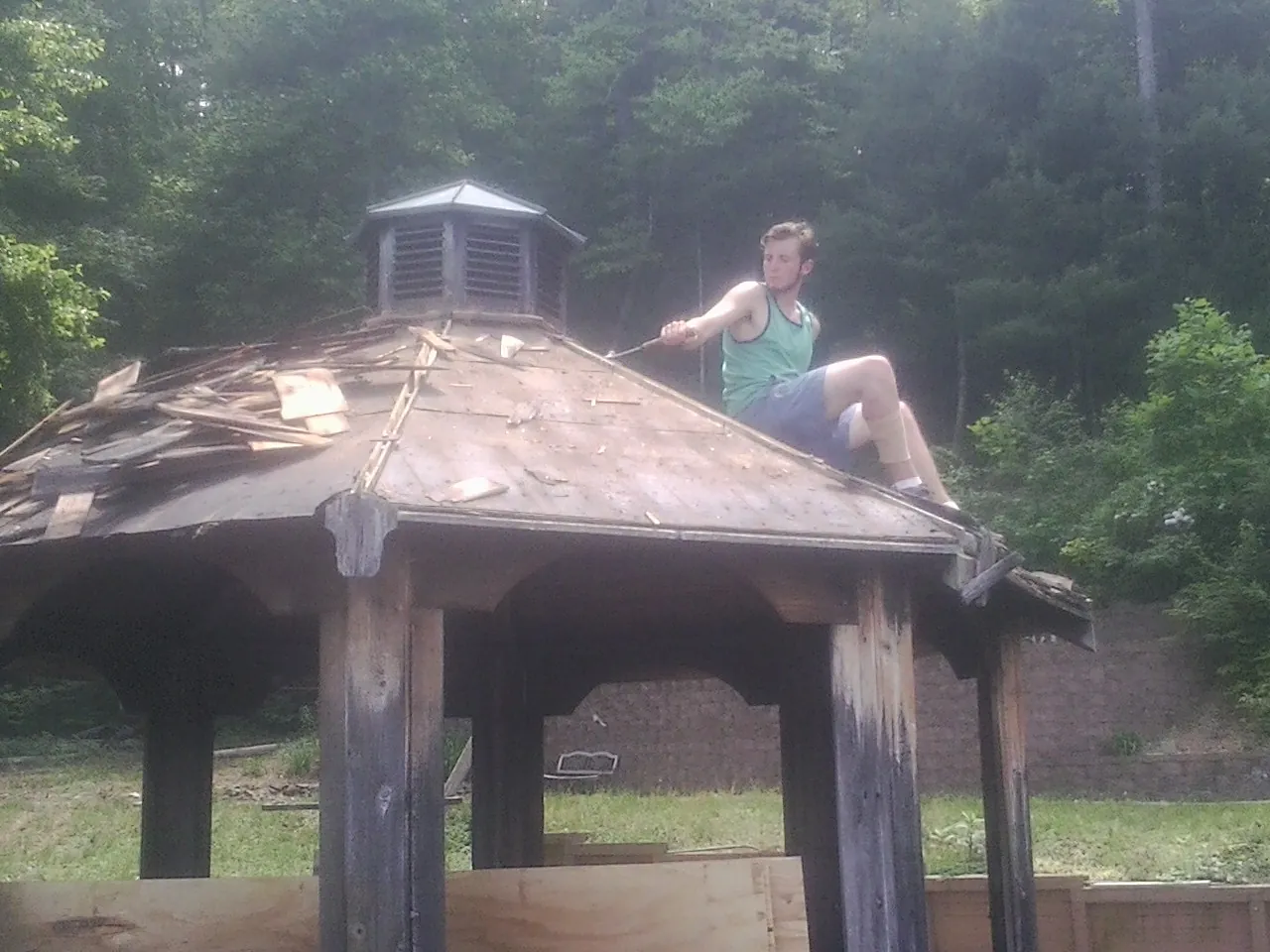 Tearing the old roof off a wooden gazebo before new shakes in Mc Gill