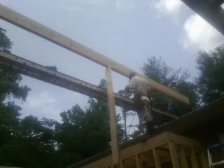 Carpenter setting a ridge beam over a new addition frame — Ice Dam Removal by Roofing Brothers in Mc Gill