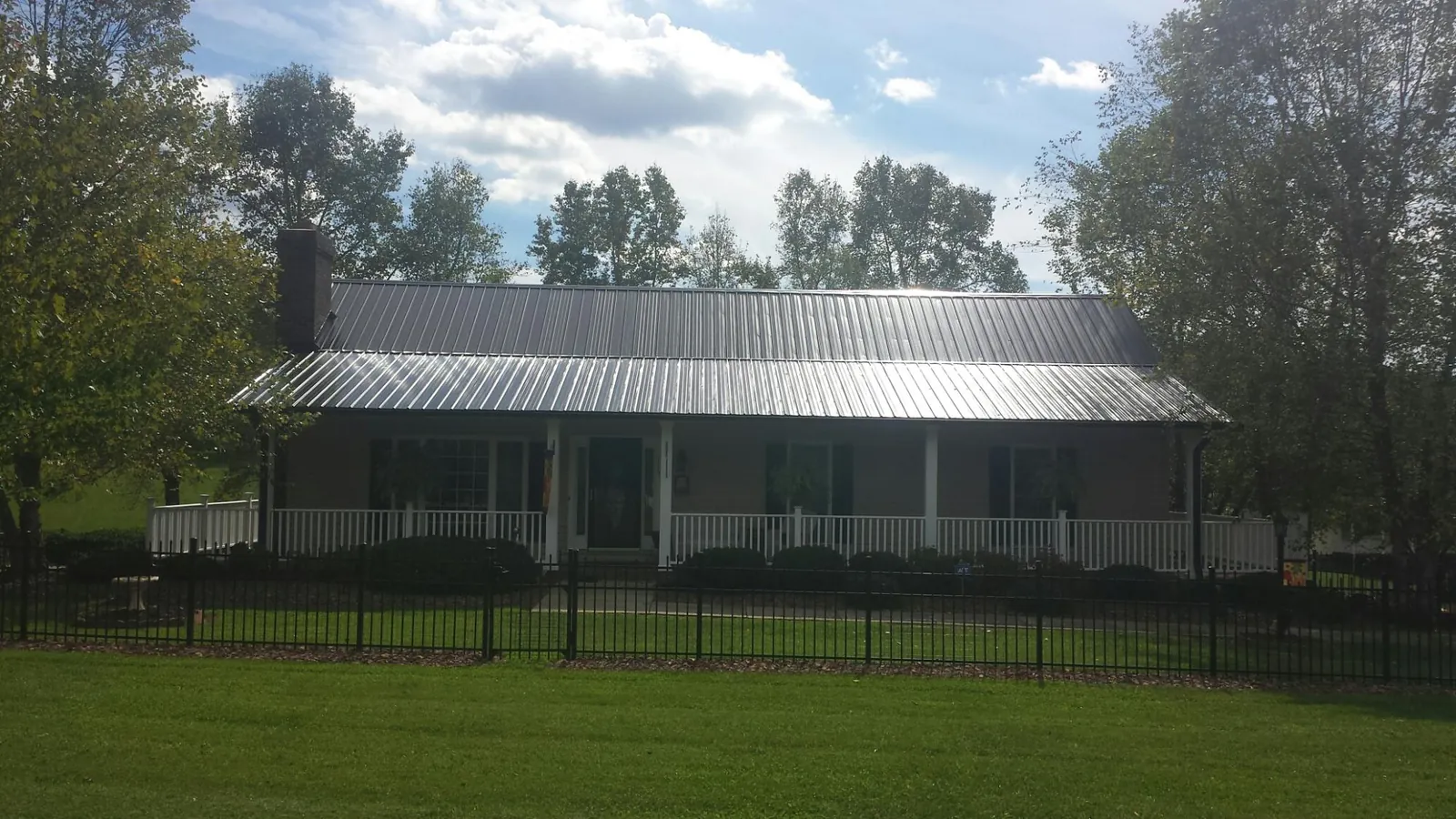 Gray metal roof on a brick ranch with a full width front porch — Gutter Guard Installation work by our crew in Mc Gill